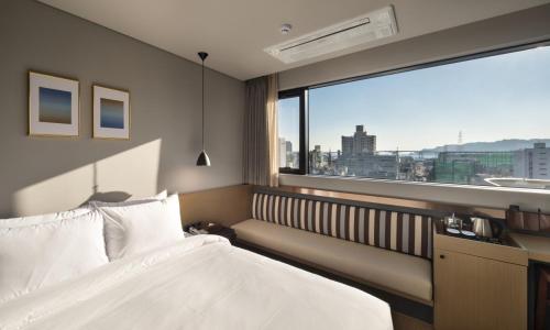 ein Schlafzimmer mit einem Bett und einem großen Fenster in der Unterkunft Bay Hound Hotel in Busan