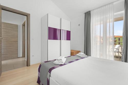 a bedroom with a large bed and a large window at LotusPoolApart in Premantura