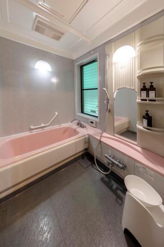 a bathroom with a pink bath tub and a toilet at BASE CAMP Kitakaruizawa in Naganohara