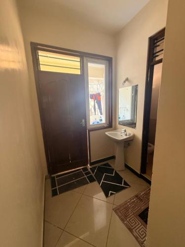a bathroom with a sink and a mirror and a door at Ahfash Homes in Mombasa
