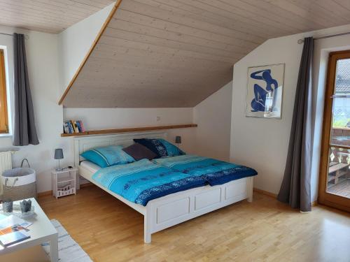 a bedroom with a bed with a blue comforter at Ferienwohnung Czanderl in Dießen am Ammersee