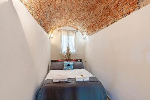 a small bedroom with a bed in a white room at La Volta Segreta in Albenga