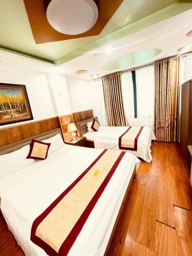 two beds in a hotel room with wooden floors at Hà Thành Luxury Hotel in Hanoi