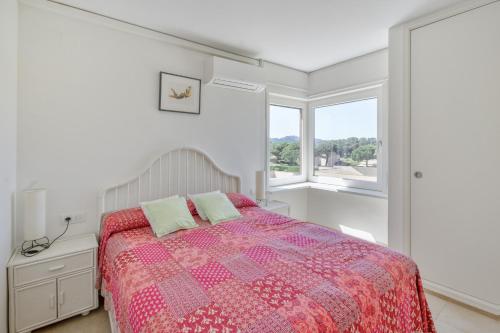 a white bedroom with a bed and two windows at Golf Mar I H5 in Pals