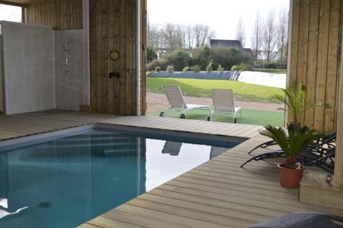 una piscina con due sedie su un ponte di legno di Gîte de LANVIAN a Guissény