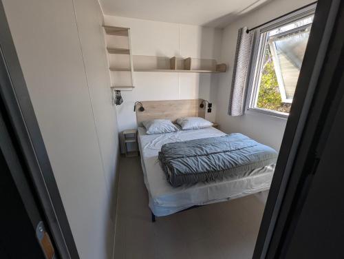a small bedroom with a bed and a window at Camping de Lanven in Plomeur