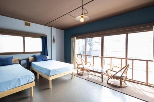 a bedroom with two beds and a balcony at KARASUYA GuestHouse in Takasaki