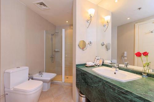 a bathroom with a sink and a toilet and a mirror at Plaza Inn Hotel in Doha