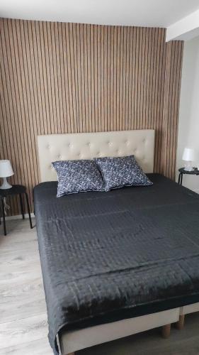 a bedroom with a bed with a black blanket and pillows at L'escapade CDG Astérix Parc d'exposition in Louvres