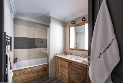 a bathroom with a tub, sink, mirror and towel rack at Hotel Village Montana by Les Etincelles in Tignes