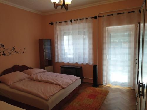 a bedroom with a bed and a window at Györkös Apartman in Balatonszárszó