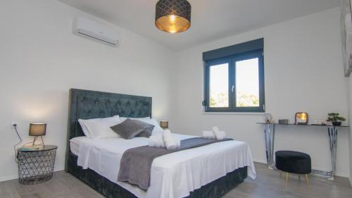 a bedroom with a bed with white sheets and a window at Villa Dani by Villas Guide in Gostinjac