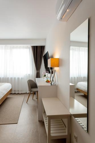 a hotel room with a desk and a mirror at Hotel Grand Asia in Walferdange