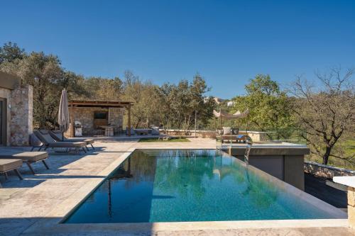 a swimming pool with blue water in a backyard at Sunny Villa-Earthen Stone Gem by etouri in Margarítai