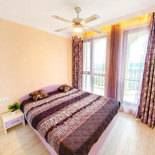 a bedroom with a bed with a ceiling fan and windows at Harmony Dream Island 9 Private Apartment 618 in Sunny Beach