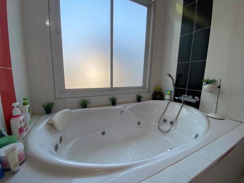 a large white tub in a bathroom with a window at Mae Wad House in Ban Oi