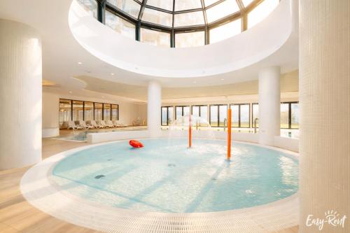 a large swimming pool in a building with a domed ceiling at Prestige 103 - z widokiem na morze - BASEN, sauna, jacuzzi w cenie pobytu! - Easy - Rent Apartments in Pobierowo