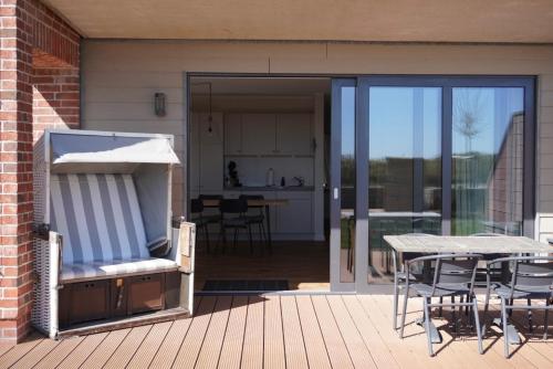 a patio with a table and chairs on a deck at Ostsee-Strandhaus-Holnis in Glücksburg