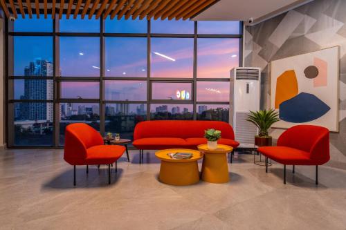 a lobby with red chairs and a table and a large window at ABC Plus Hotel & Homes in Cebu City