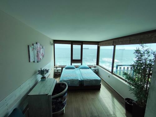 a bedroom with two beds and a balcony with the ocean at Hemingway rooms in Happy Beach in Varna City