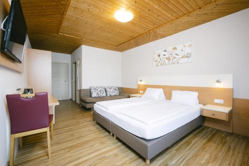 a bedroom with a bed and a desk and a couch at Pension Seehof in Holzöster