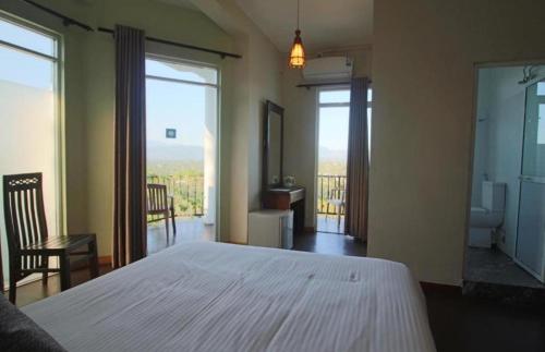 a bedroom with a white bed and a balcony at Villa Arunalu Kandy in Kandy
