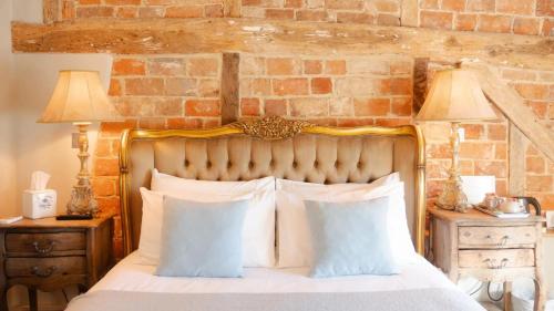 a bed with two pillows and a brick wall at Broad Leys in Aylesbury