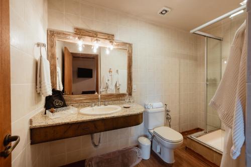 a bathroom with a sink and a toilet and a mirror at Petit Casa da Montanha in Gramado