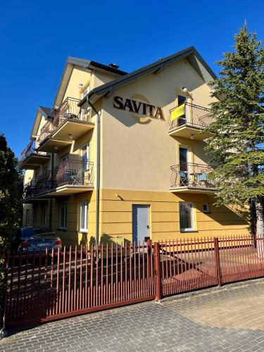 a yellow building with a fence in front of it at SAViTA in Karwia