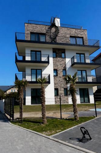 a tall building with palm trees in front of it at Apartament Kaszubska Bryza III - HEL in Hel