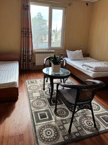 a room with two beds and a table and chairs at Жетиген in Karakol