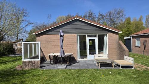 a house with a patio with a table and an umbrella at Zilt vakantiehuisje - Rekerlanden 283 in Schoorldam