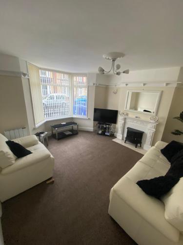a living room with two white couches and a fireplace at Rosie’s rest in Bridlington