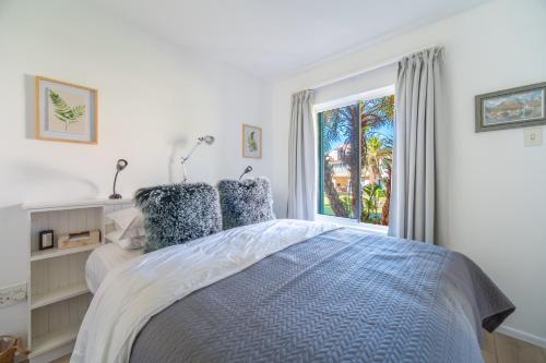 a white bedroom with a bed and a window at Zenith Place, Port St Francis in Cape St Francis