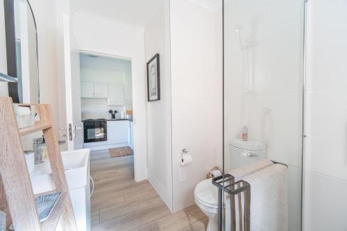 a white bathroom with a toilet and a kitchen at Zenith Place, Port St Francis in Cape St Francis