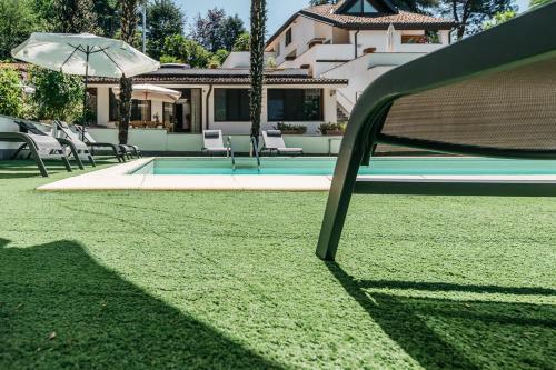 a pool with chairs and an umbrella in front of a house at Villa Pegasus in Turin