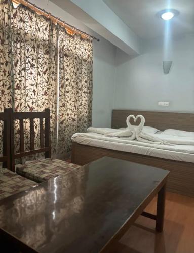 a room with two beds and a table and chairs at Hotel imroz in Srinagar
