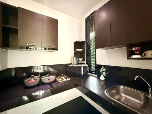 a kitchen with brown cabinets and a sink at Westkey Kamala Hotel in Kamala Beach