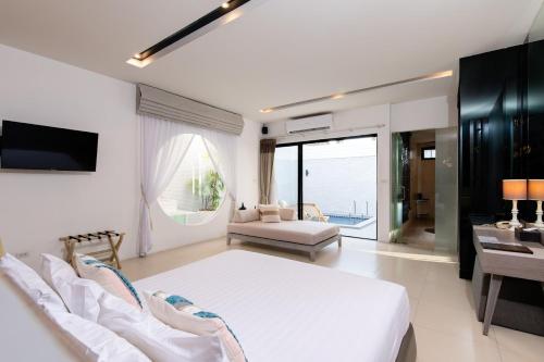 a bedroom with a white bed and a living room at Cae Villa Hua Hin in Hua Hin