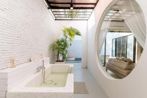 a bathroom with a tub and a round mirror at Cae Villa Hua Hin in Hua Hin