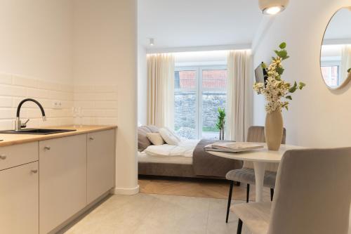a kitchen and living room with a table and a bed at Starowiejska Residence 1860 in Miejsce Piastowe
