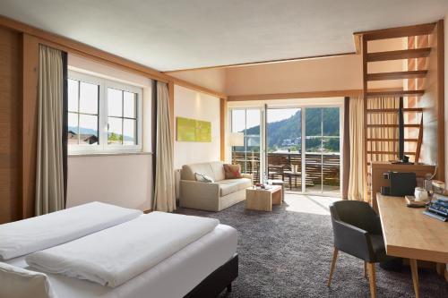 a hotel room with a bed and a desk and a chair at Panoramahotel Oberjoch in Bad Hindelang