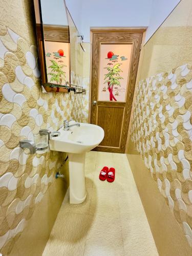 a bathroom with a sink and red slippers in it at Kings Garden House in Weligama