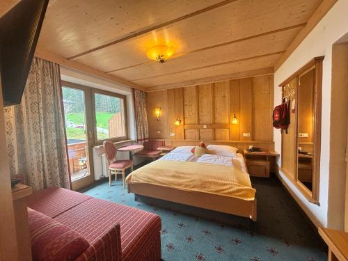 a bedroom with a bed and a desk and a table at Hotel Bergkristall in Oberau