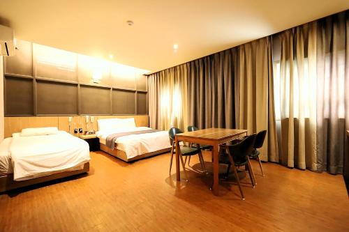 a hotel room with two beds and a table at Ingye Joy Hotel in Suwon