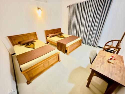 two beds in a room with a table and a chair at Kings Garden House in Weligama