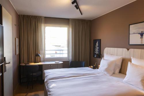 a hotel room with a bed and a desk and a window at Scandic Stuttgart Europaviertel in Stuttgart