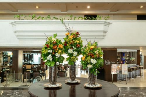 three vases with flowers on a table in a building at L'Fisher Hotel Bacolod in Bacolod