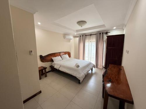 a bedroom with a bed and a table and a window at Upland Estates Serviced Apartments in Lusaka