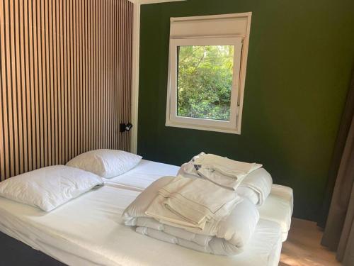 a bedroom with a bed with white sheets and a window at Outdoors Holten - Forest Cabin in Holten